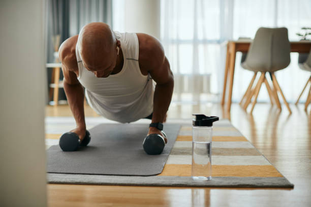 istock African American athlete using hand weights while exercising push-ups at home. 1418398232