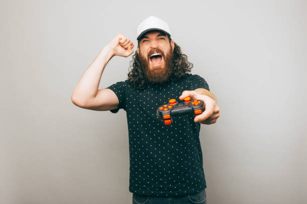 istock Excited gamer is holding his console and celebrating his win over a gray wall 1418402877