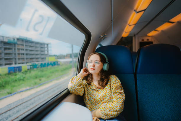 woman listening to music in headphones while  traveling in the train - trein nederland stockfoto's en -beelden
