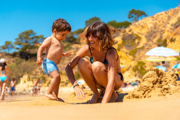 мать и сын играют на пляже в прайя-ду-барранку-дас-белхарукас, албуфейра, алгарве. португалия - алгарве стоковые фото и изображения