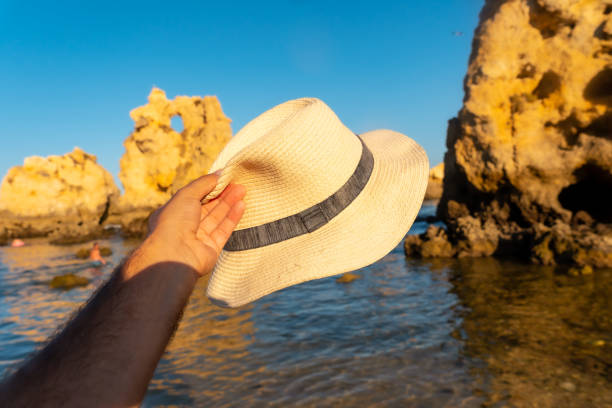 со шляпой на пляже аррифес, пляж алгарве, албуфейра. португалия - алгарве стоковые фото и изображения