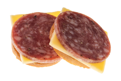 Side view of two snack crackers with dry salami and gouda cheese isolated on a white background.