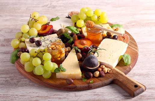 Cheese board: appetizers board with assorted cheese, fruits, honey and nuts -charcuterie board