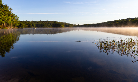 Sanborn Pond in Maine in the early morning with fog on the water in the early spring.