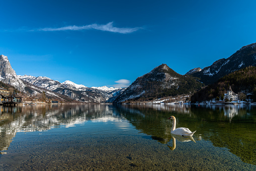 Stunning panorama view of Grundlsee lake with snow covered mountain peaks of Styrian Alps in background on a sunny winter day, Ausseerland - Salzkammergut region, Styria, Austria