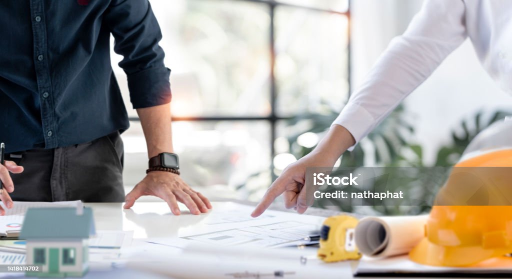 Hands of creative team discussing plan of the building. Architects or engineering discussing project together at the meeting in the office. Building Contractor Stock Photo