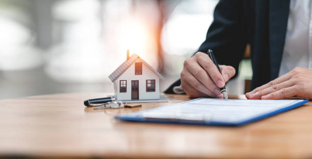istock Real estate concept - businessman signs contract behind home architectural model 1418414921