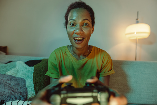 Close up shot of Mid adult African-American man playing video games while sitting on the sofa at home