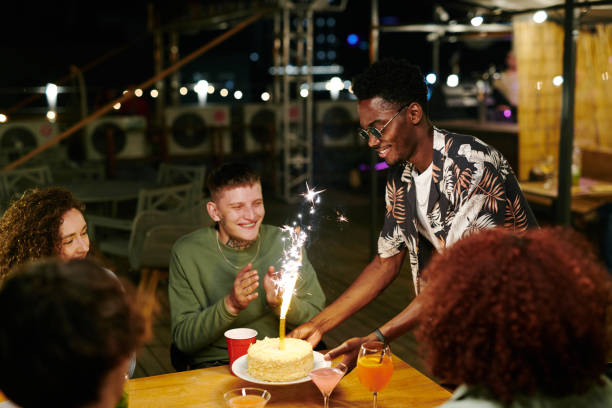 feliz joven afroamericano poniendo plato con pastel en la mesa festiva - birthday cake five people party fotografías e imágenes de stock