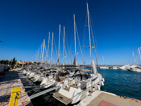 Lavrio, Greece, 07/29/2022; Panorama of a yacht marina in quiet fishing town, southeastern part of Athens, Greece. Ships are moored at the port on a sunny, clear day. Tourist charter boat business. Sea vacation rental background with copy space.