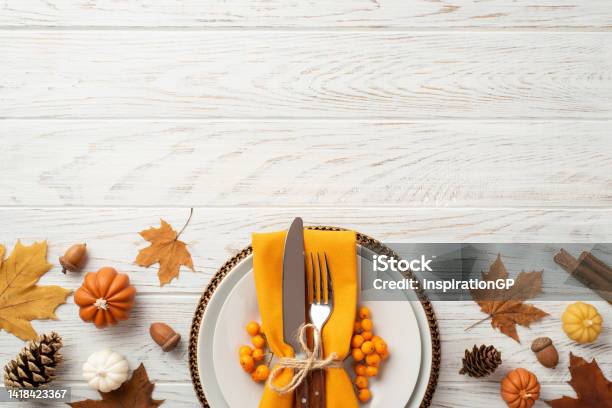 Thanksgiving Day Concept Top View Photo Of Plate Cutlery Fork Knife Napkin Rowan Maple Leaves Pine Cones Acorns Pumpkins And Cinnamon Sticks On Isolated White Wooden Table Background With Copyspace Stock Photo - Download Image Now