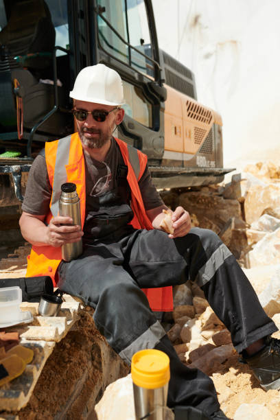 istock Middle aged male engineer in workwear and hardhat having sandwich and hot tea 1418436698