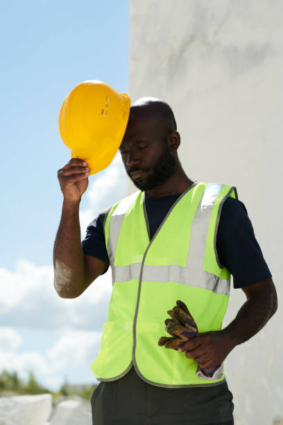 istock Bald African AMerican engineer in uniform putting safety helmet on his head 1418436741