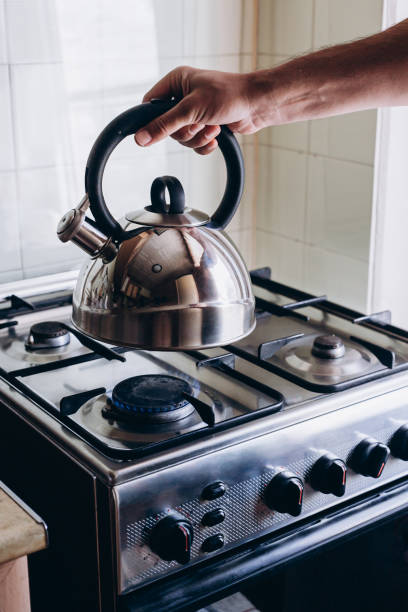istock Man's hand puts the kettle on the gas burner 1418437070
