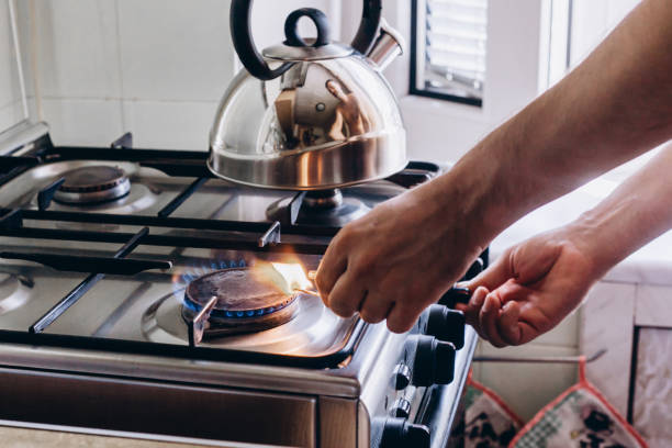 une main d’homme avec une allumette allume un brûleur à gaz ou une cuisinière à gaz dans la cuisine - natural gas gas burner flame photos et images de collection