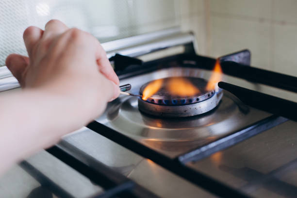 une main de femme avec des allumettes allumettes cuisinière à gaz dans son appartement - natural gas gas burner flame photos et images de collection