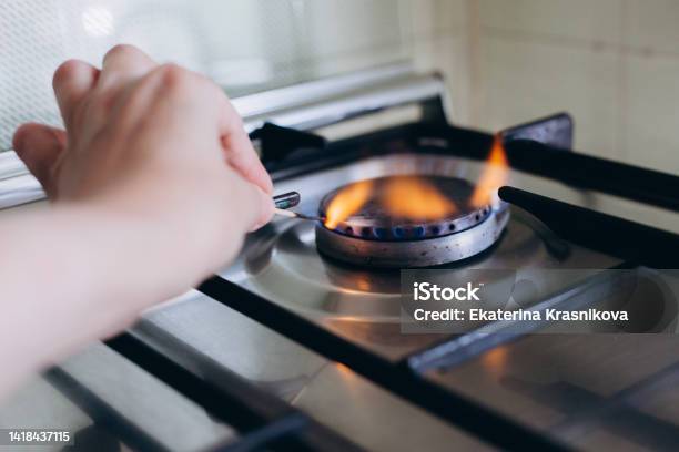 A Womans Hand With Matchstick Lights Gas Stove In Her Apartment Stock Photo - Download Image Now