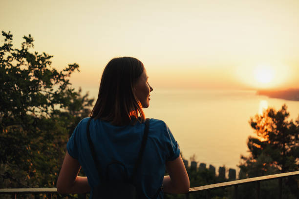 istock Woman looking at scenic orange sunset on the beach 1418450197