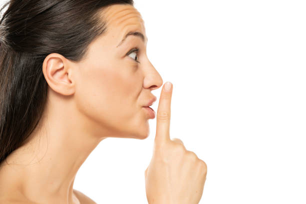 istock Excited young  woman with a finger on her lips 1418454433