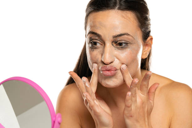 istock Young woman applies face cleaning product before remove it 1418454493