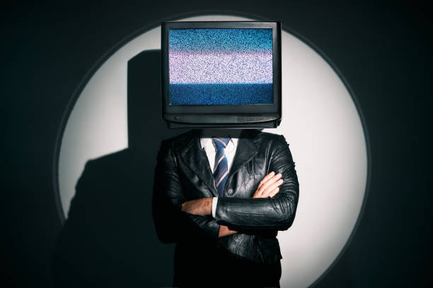 Man with TV instead of head. Media zombie concept Man with TV instead of head. Media zombie concept with television addicted male in black coat with crossed arms posing on studio in the spotlight. Conceptual, contemporary art collage. Surrealism constituency photos stock pictures, royalty-free photos & images
