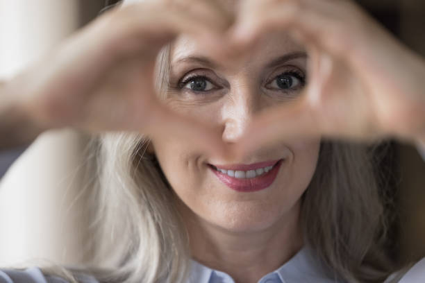 istock Happy lady looking at camera through hand heart at eyes 1418459667