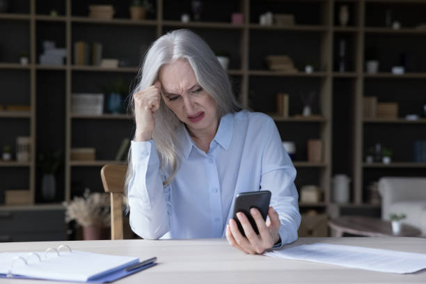 istock Frustrated annoyed elderly retired woman holding wrong working mobile phone 1418459713