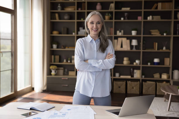 istock Confident mature elderly business woman standing at work table 1418459761