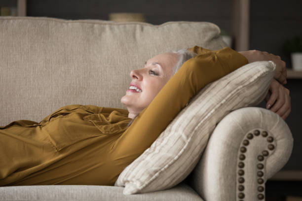 istock Happy cheerful mature woman lying on comfortable couch 1418459812