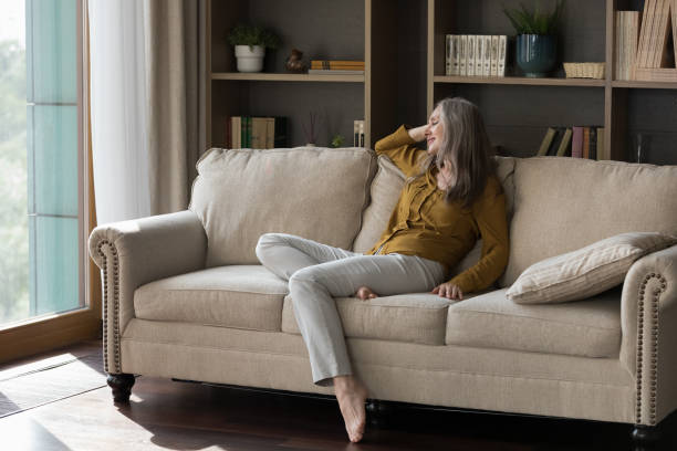 istock Happy beautiful grey haired elderly woman sitting on comfortable couch 1418459841