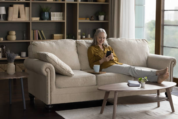 istock Happy joyful mature woman using mobile phone at home 1418459913