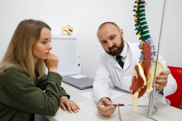 istock Male doctor explaining spine model to young patient 1418461403