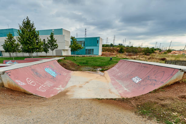 beton-skatepark skatepark leer, mit bäumen etwas graffiti und bewölktem himmel - skateboard park ramp skateboard graffiti stock-fotos und bilder