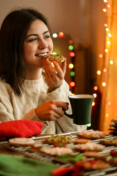 istock Young woman eating gingerbread cookies 1418473699