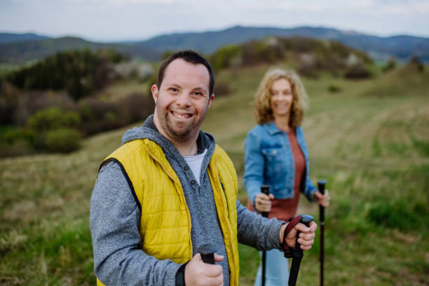Portrait of happy young man with Down syndrome with his mother hiking together in nature. A portrait of happy young man with Down syndrome with his mother hiking together in nature. disabled person hiking outdoors stock pictures, royalty-free photos & images