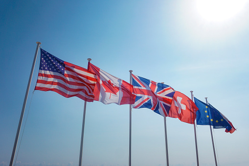 Flags of USA, Canada, UK, Switzerland, EU and France waving in the wind.