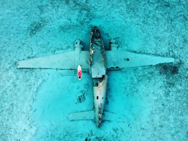 A woman paddleboarding around the wreckage of a plane that landed in the water off of Norman's Cay in 1980.
This site is now a popular destination for snorkeling.