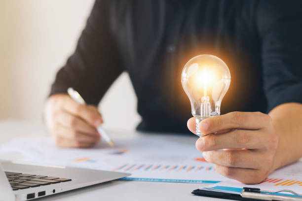 istock Successful Innovation through ideas and inspiration ideas. Human hand holding light bulb to illuminate, idea of creativity and inspiration concept of sustainable business development. 1418475815