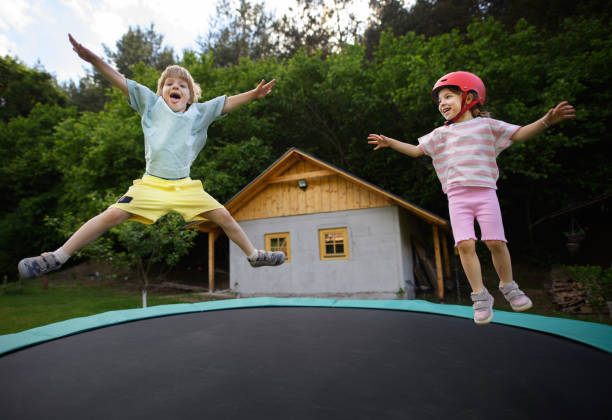 istock Little siblings enjoy jumping on trampoline - outside in backyard 1418481168