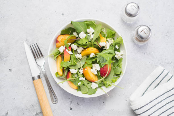 istock A light summer salad of rucolla, peaches and cheese on a light gray background. 1418481884