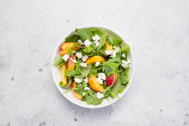 istock A light summer salad of rucolla, peaches and cheese on a light grey background. 1418481888