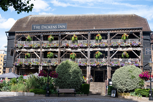 London, UK - June 26, 2022: The Dickens Inn, a public house located at the St. Katherine Docks in the Docklands area in central London. The Docklands and is now a popular housing and leisure complex. Bedecked with flowers, the Dickens Inn is popular with tourists.