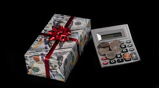 Isolated gift box wrapped in wrapping paper with 100 dollar bill picture on black background