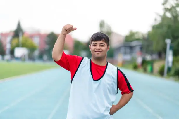 Young male athlete with Down syndrome posing at sport track