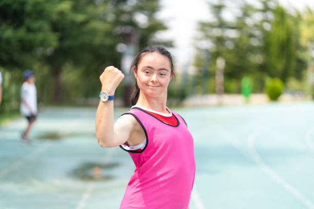 Young female athlete with Down syndrome posing at sport track and Flexing Muscles Young female athlete with Down syndrome posing at sport track and Flexing Muscles paralympic games stock pictures, royalty-free photos & images