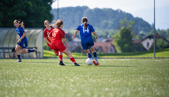 Shot of female soccer player kicking the ball during a match on a stadium. Sport and healthy lifestyle concept.