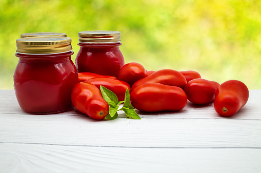 Traditional Italian tomato sauce in a glass jar with fresh tomatoes and basil. Copy space.