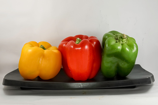 Green, red, yellow bell peppers on black platter