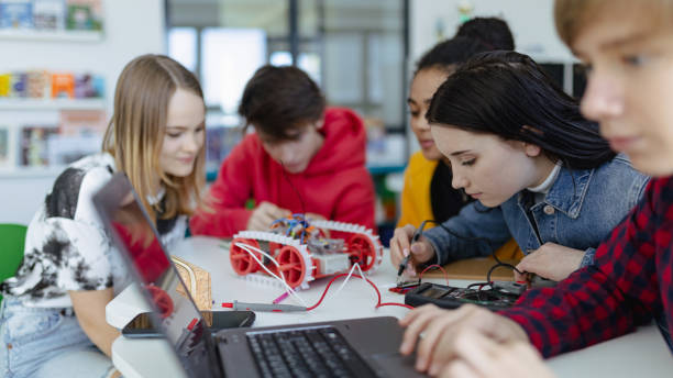 istock Group of high school students building and programming electric toys and robots at robotics classroom 1418490614