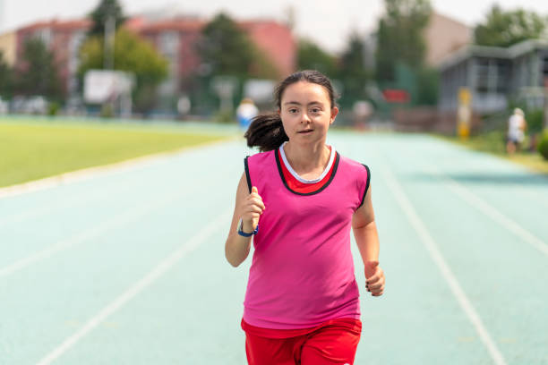 Young female athlete with Down syndrome running a track race Young female athlete with Down syndrome running a track race paralympic games stock pictures, royalty-free photos & images